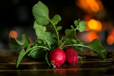 Close-up of fresh radishes with leaves on a wooden table, highlighting freshness.