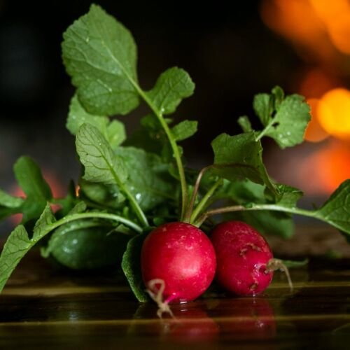 Close-up of fresh radishes with leaves on a wooden table, highlighting freshness.